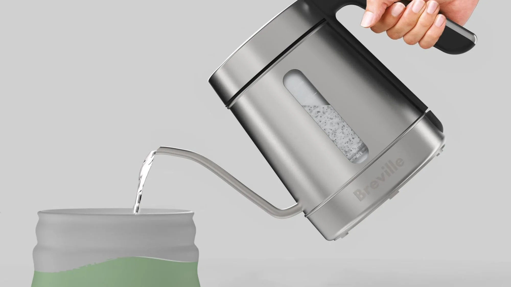 Water pouring from the gooseneck spout into a matcha bowl, the stream landing in a clean column.