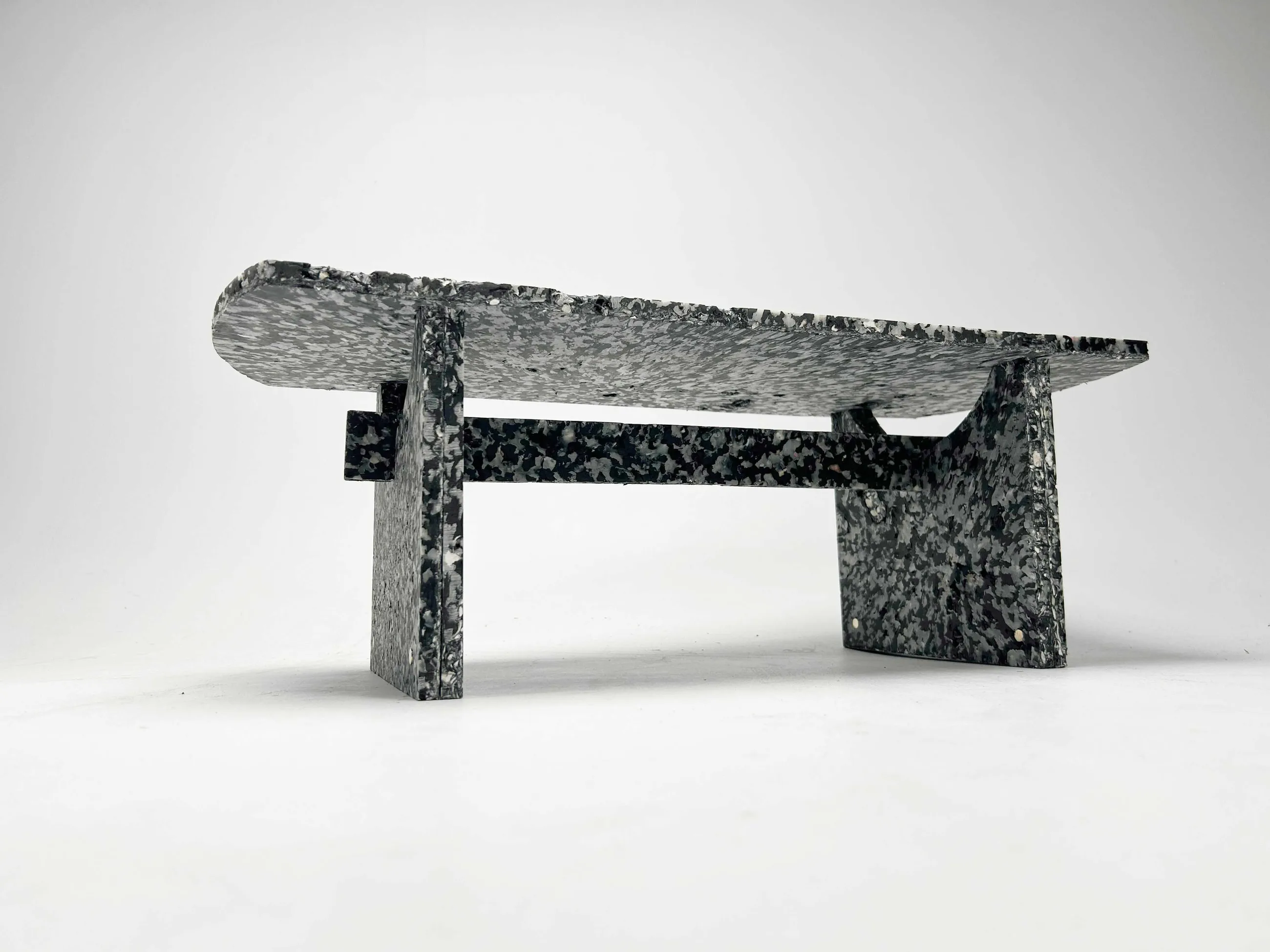 The finished Shio bench in three-quarter view, its speckled composite surface catching the light.